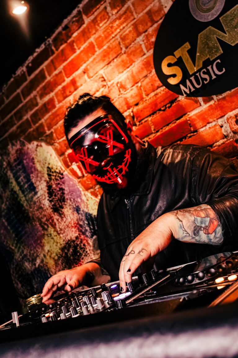 DJ com máscara de LED vermelha toca na cabine — Sad Baile Curitiba Halloween, 10/10/2026