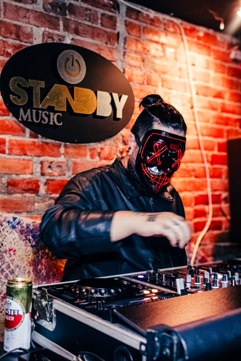 DJ mascarado mixando em frente à parede de tijolos — Sad Baile Curitiba Halloween, 10/10/2026
