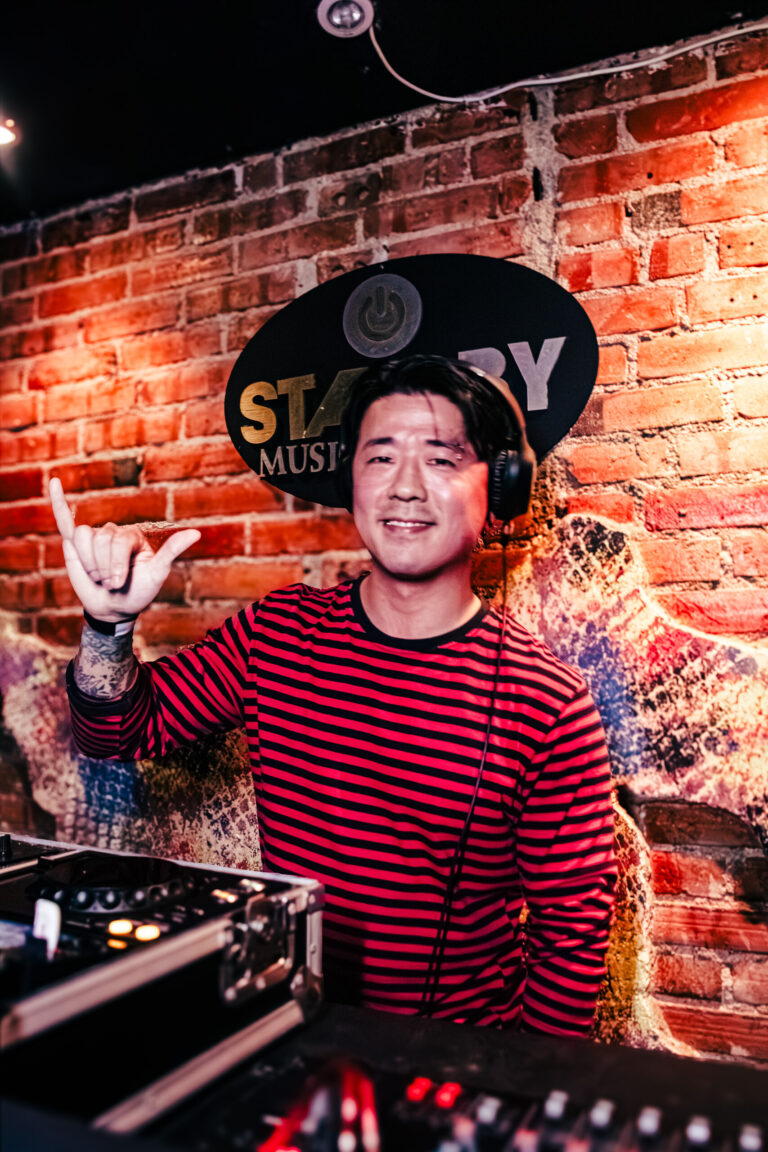 DJ sorri e faz sinal de rock na cabine — Sad Baile Curitiba Halloween, 10/10/2026