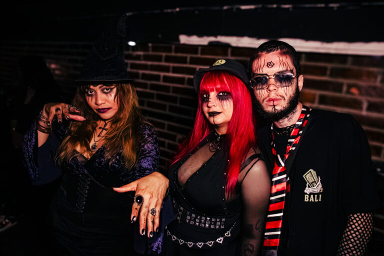 Trio de amigos fantasiados em frente à parede de tijolos — Sad Baile Curitiba Halloween, 10/10/2026