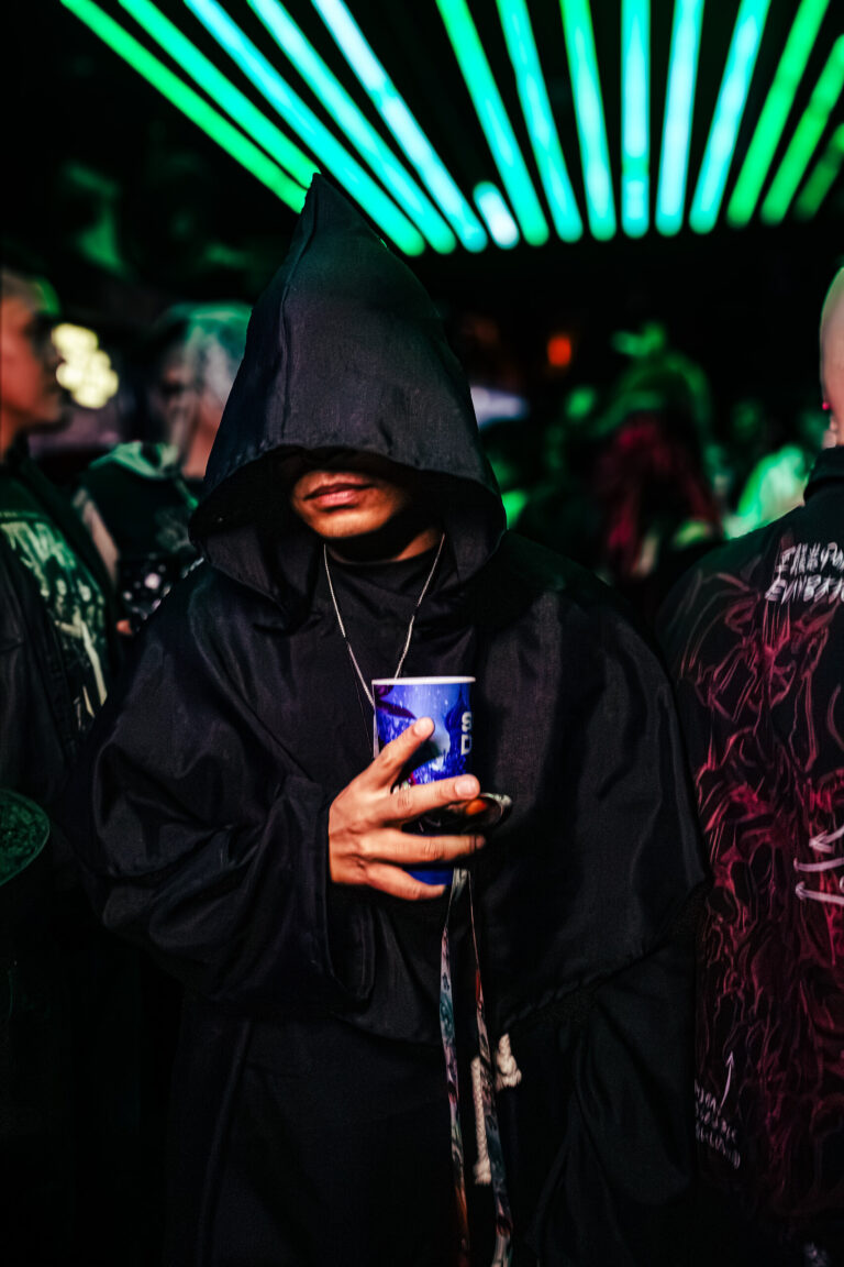 Pessoa de capuz preto segura copo na pista — Sad Baile Curitiba Halloween, 10/10/2026