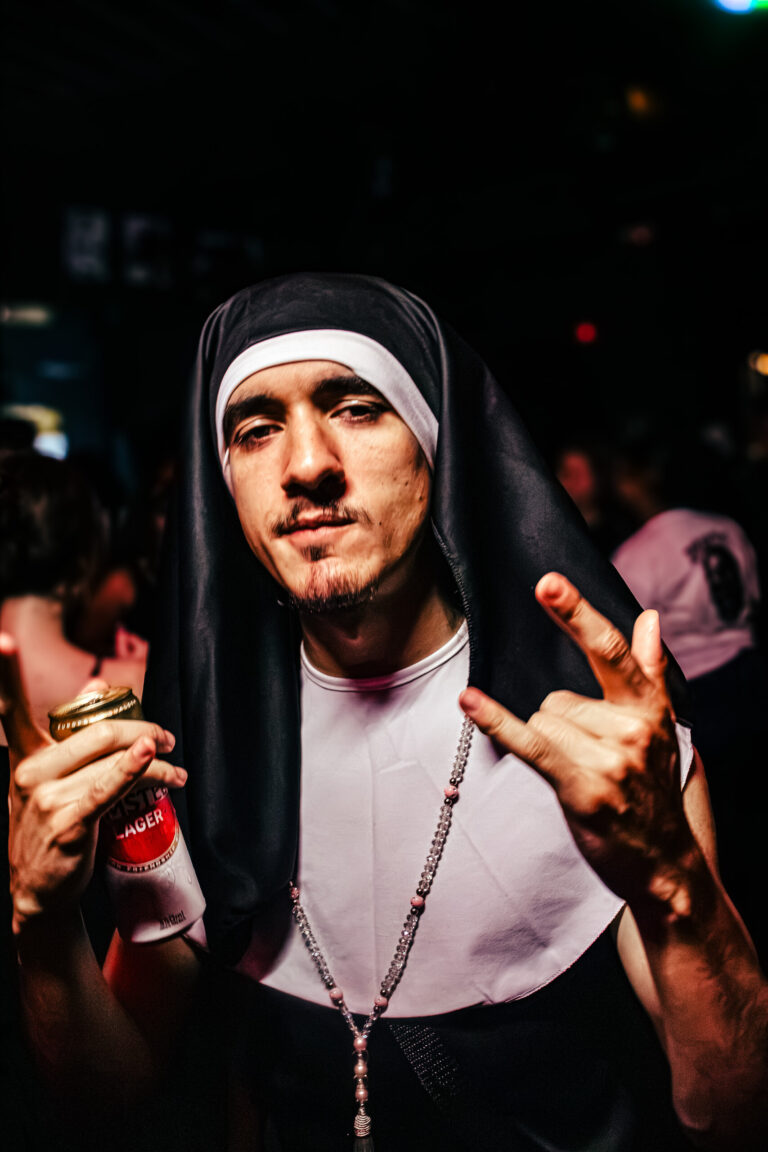 Rapaz fantasiado de freira faz sinal com as mãos — Sad Baile Curitiba Halloween, 10/10/2026