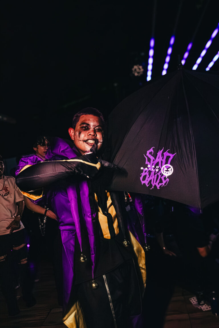 Pessoa de fantasia roxa segura guarda-chuva da Sad Baile — Sad Baile Curitiba Halloween, 10/10/2026