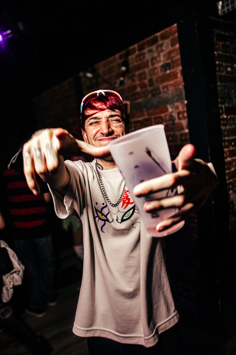 Rapaz estende o copo na direção da câmera — Sad Baile Curitiba Halloween, 10/10/2026