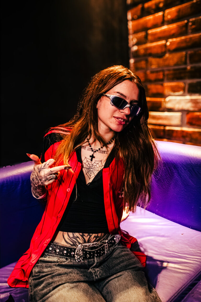 Garota de camisa vermelha e óculos escuros no sofá — Sad Baile Curitiba Halloween, 10/10/2026