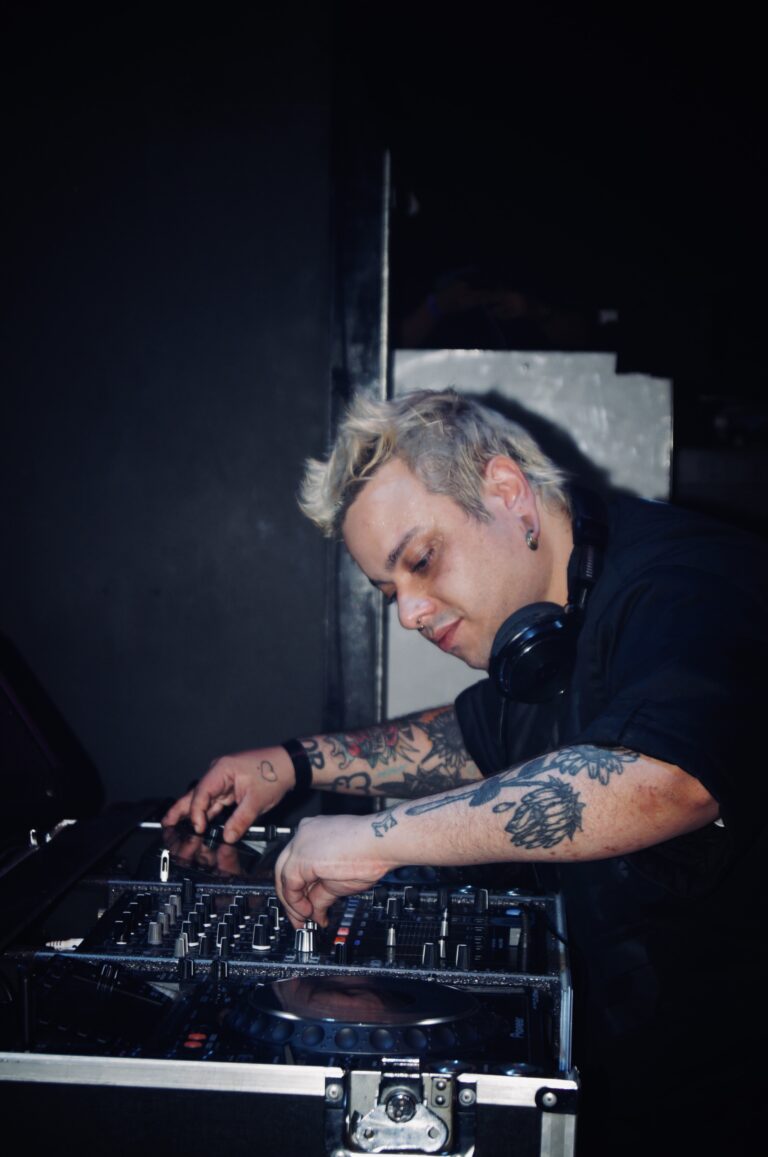 DJ de cabelo platinado ajusta os controles — Sad Baile Joker, Halloween em São Paulo, 17/10/2026