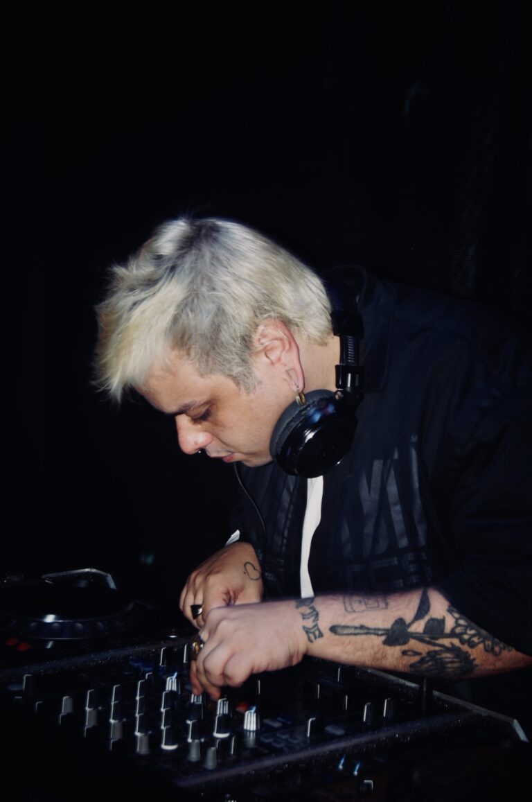 DJ de cabelo platinado mixando com tatuagens no braço — Sad Baile Joker, Halloween em São Paulo, 17/10/2026
