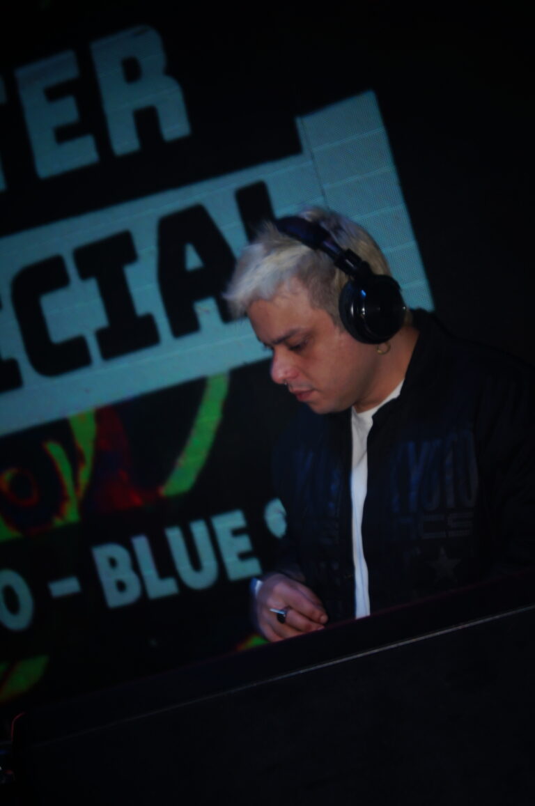 DJ de cabelo platinado diante do telão do after oficial — Sad Baile Joker, Halloween em São Paulo, 17/10/2026