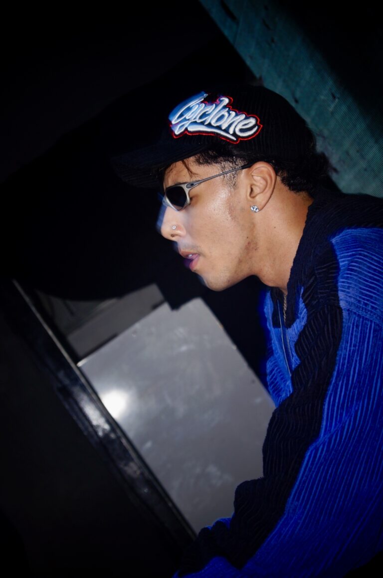 DJ de boné, óculos e jaqueta azul nos controles — Sad Baile Joker, Halloween em São Paulo, 17/10/2026