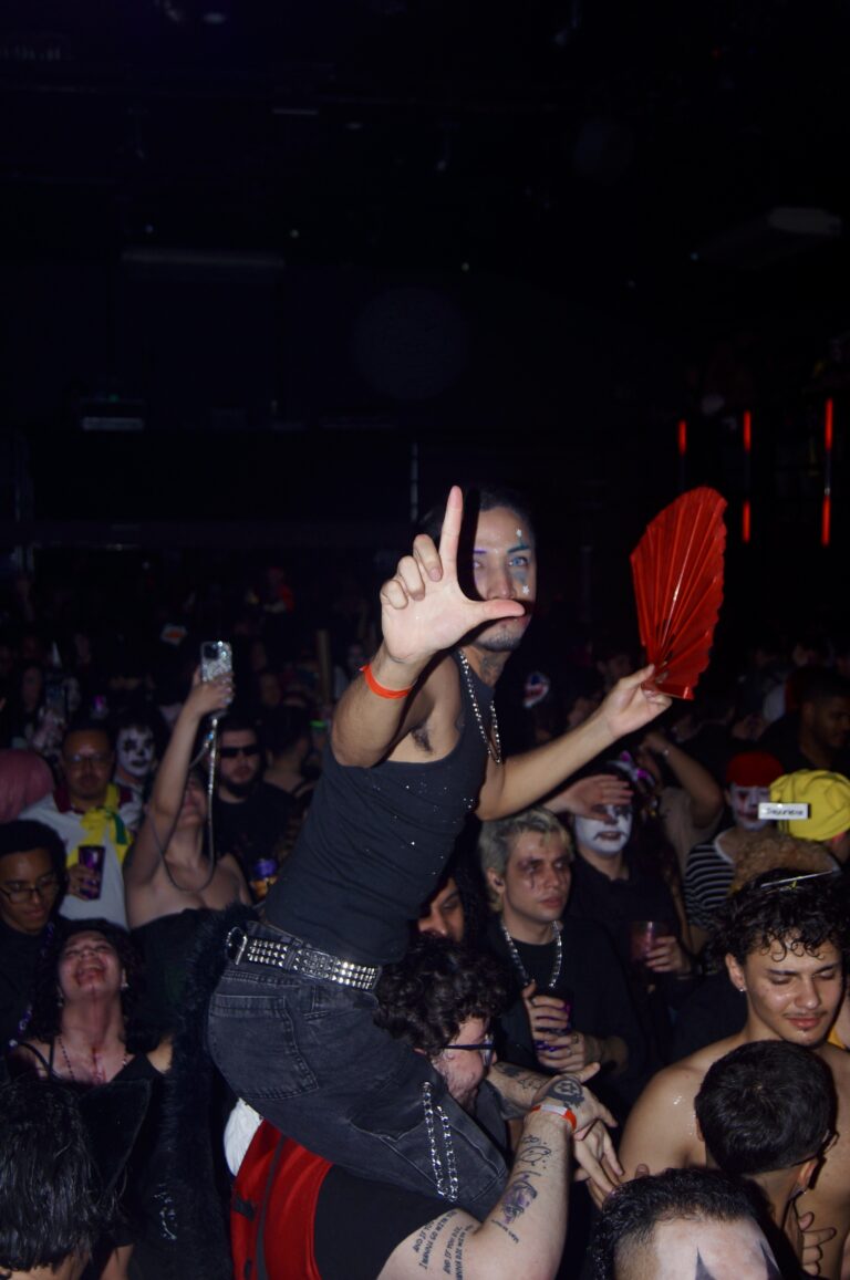 Garota de óculos escuros faz sinal de L no meio da galera — Sad Baile Joker, Halloween em São Paulo, 17/10/2026