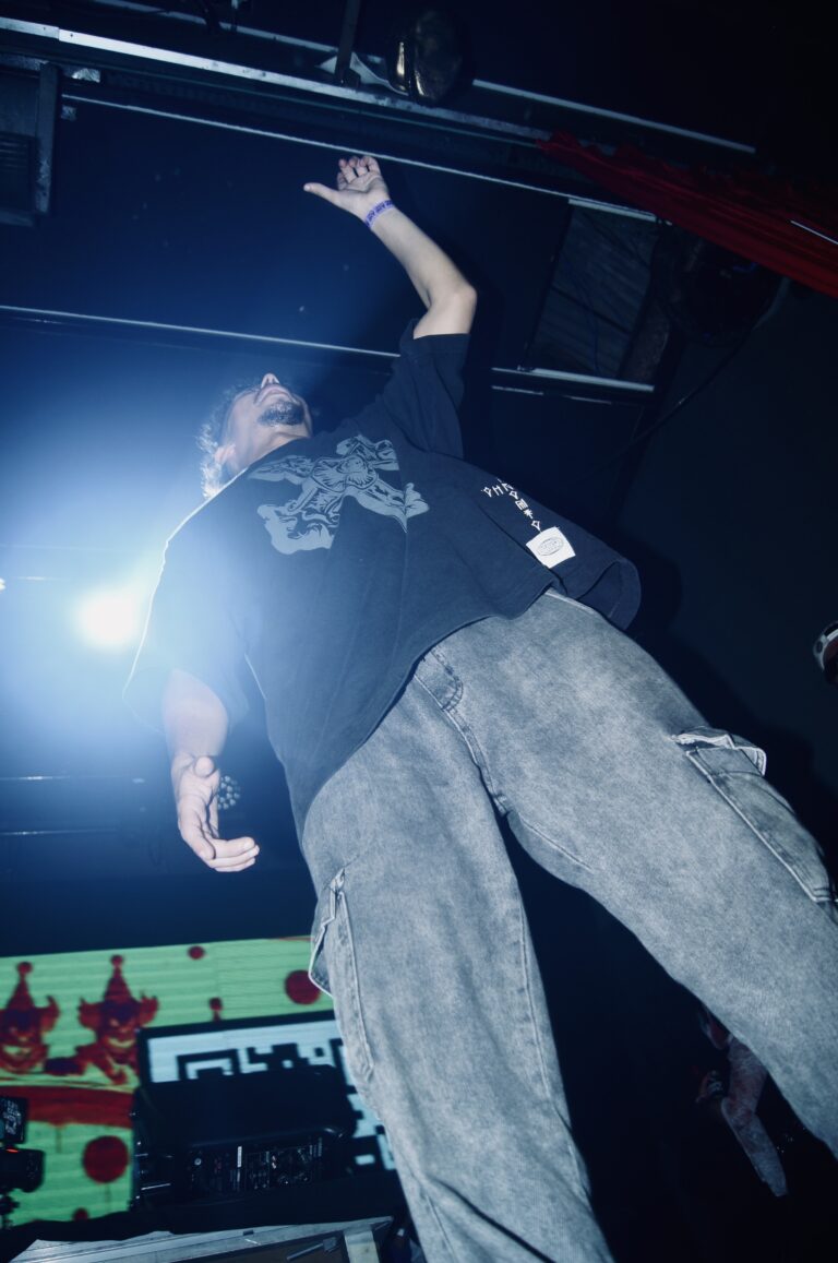 Artista de calça bege ergue o braço no palco — Sad Baile Joker, Halloween em São Paulo, 17/10/2026