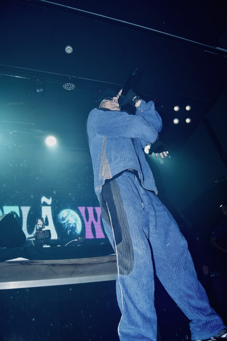 Rapper de conjunto jeans de costas canta diante do telão — Sad Baile Joker, Halloween em São Paulo, 17/10/2026