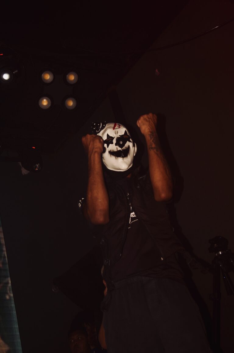 Artista com máscara de caveira ergue os punhos — Sad Baile Joker, Halloween em São Paulo, 17/10/2026