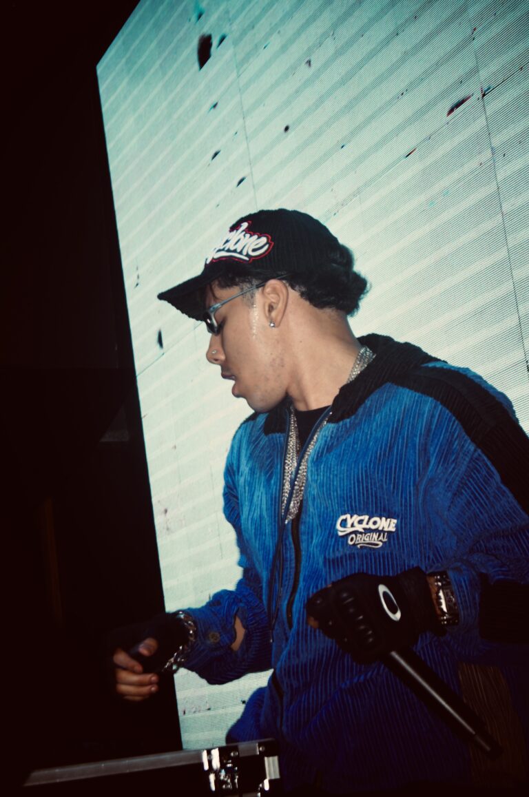 DJ de boné e jaqueta azul diante do telão branco — Sad Baile Joker, Halloween em São Paulo, 17/10/2026