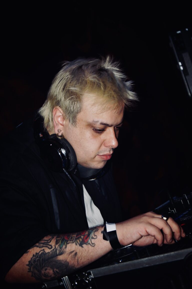 DJ de cabelo platinado e fones nos controles — Sad Baile Joker, Halloween em São Paulo, 17/10/2026
