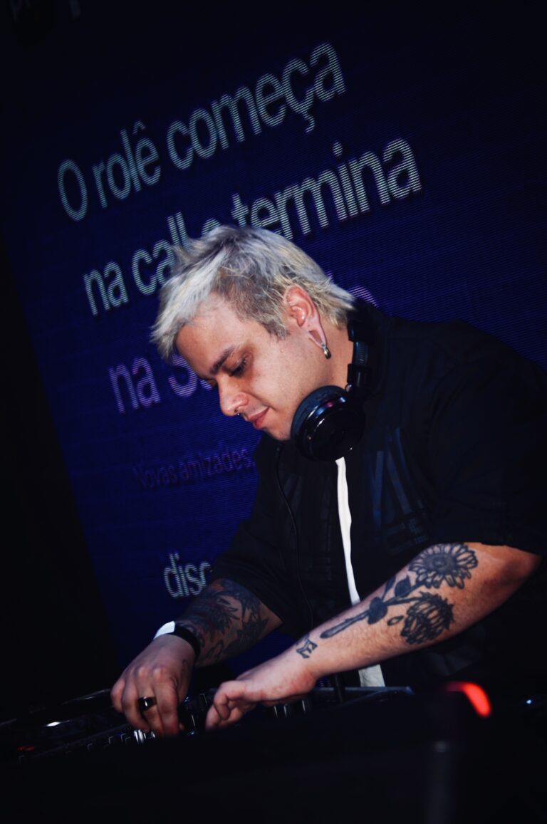 DJ diante do telão azul com a frase da festa — Sad Baile Joker, Halloween em São Paulo, 17/10/2026