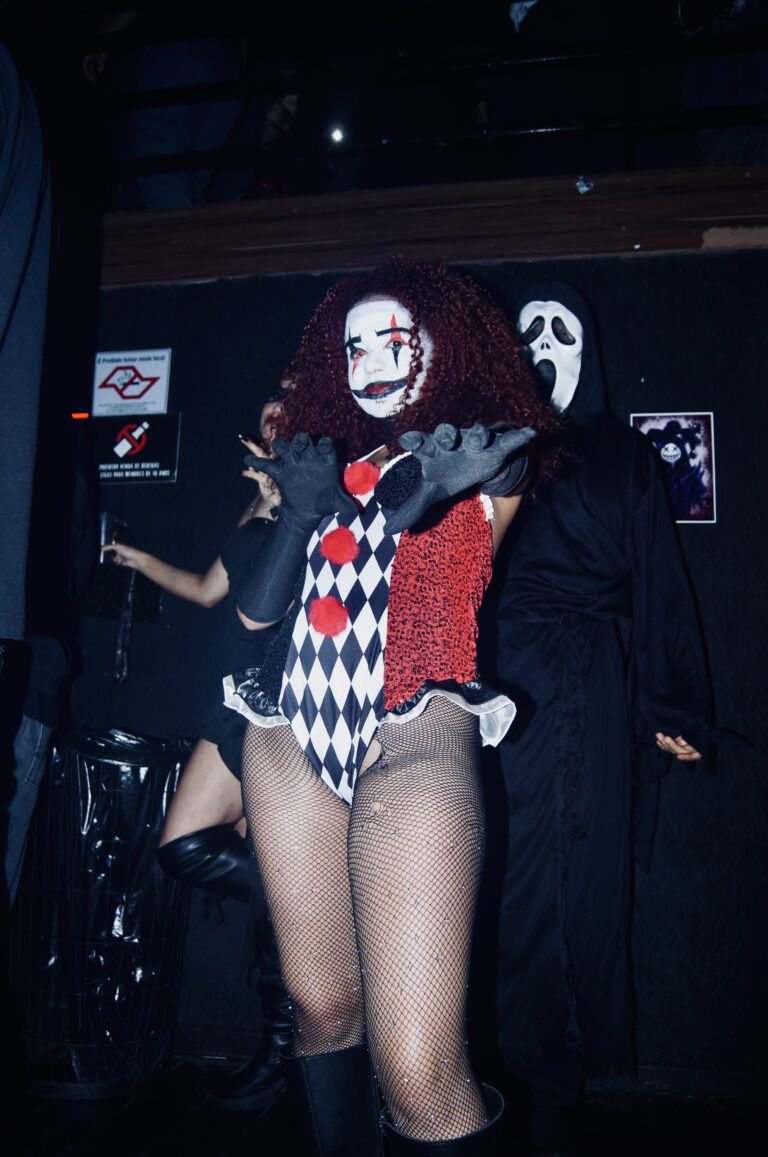 Fantasia de Arlequina de peruca ruiva com Ghostface ao fundo — Sad Baile Joker, Halloween em São Paulo, 17/10/2026