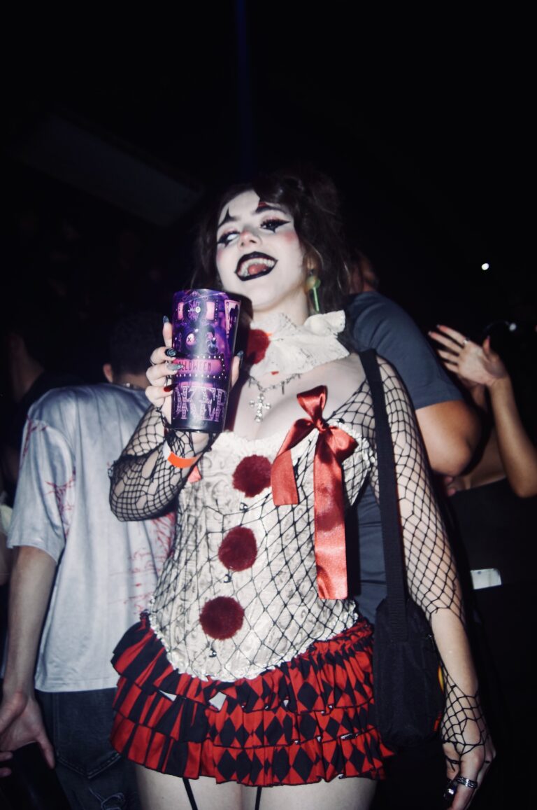 Boneca segura copo Joker e sorri — Sad Baile Joker, Halloween em São Paulo, 17/10/2026