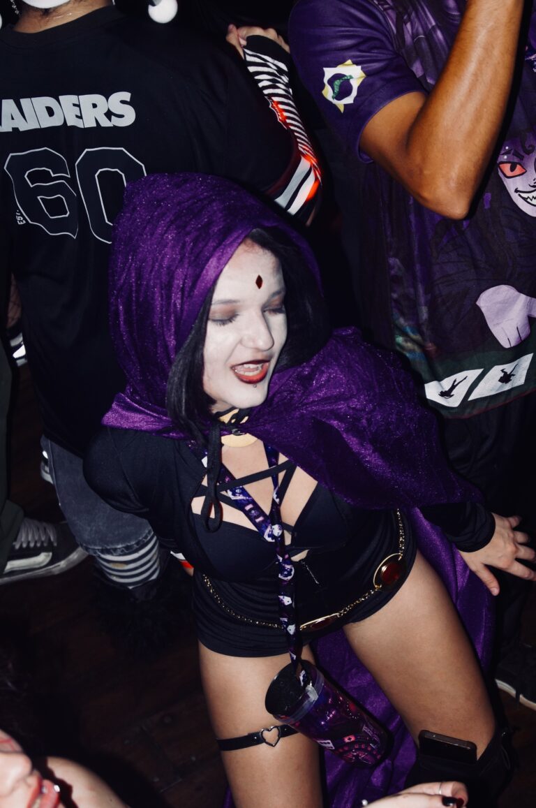 Ravena de capa roxa sorri na pista — Sad Baile Joker, Halloween em São Paulo, 17/10/2026