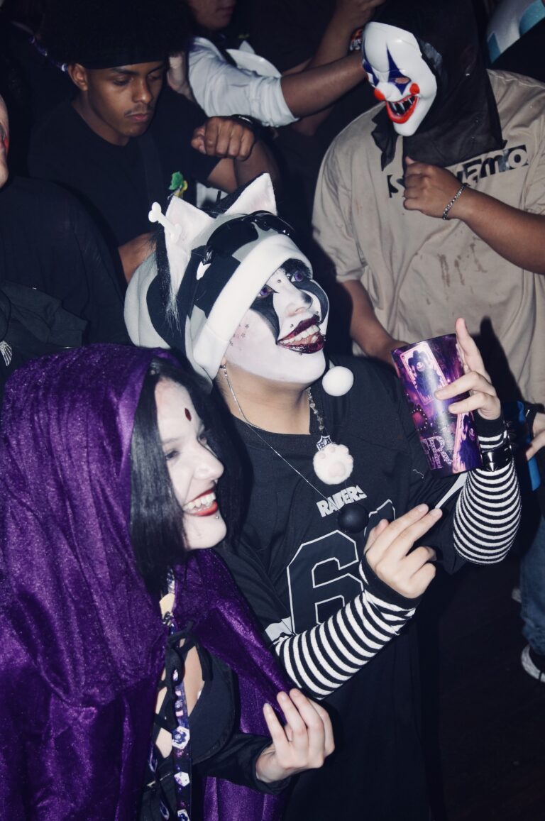 Palhaça de rosto pintado com copo Joker e amiga de cabelo roxo — Sad Baile Joker, Halloween em São Paulo, 17/10/2026