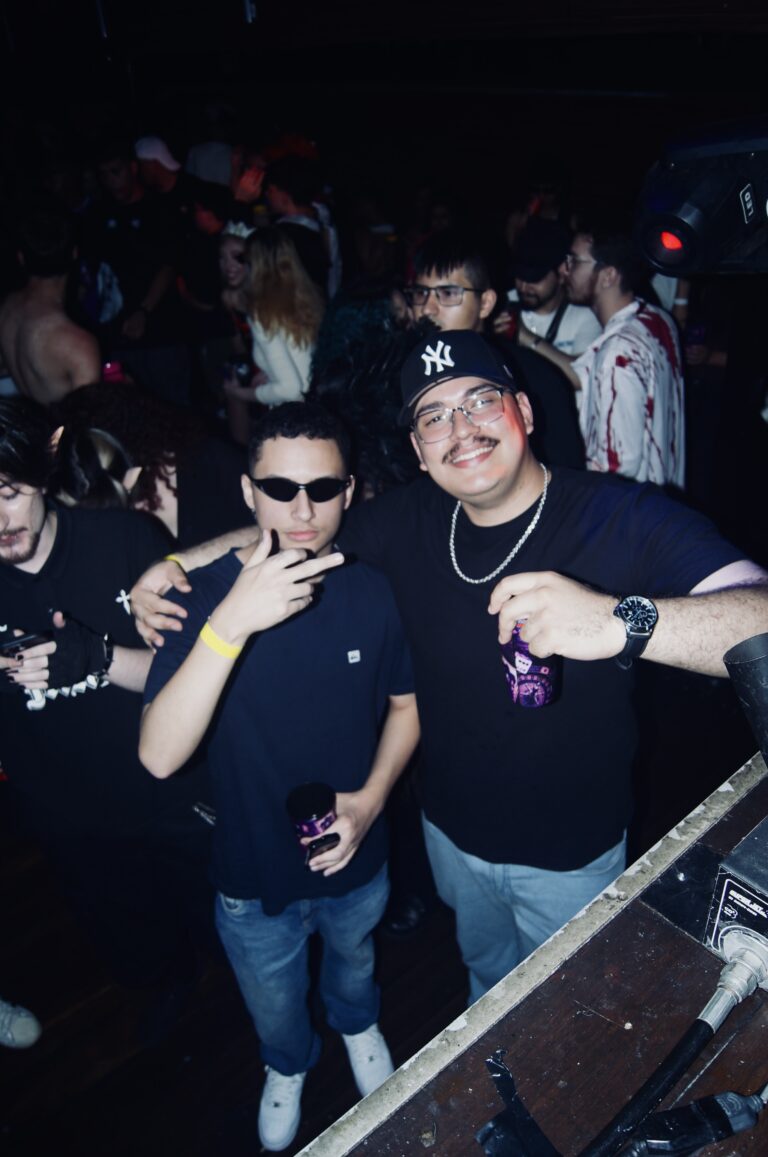 Amigos de óculos escuros fazem pose perto do palco — Sad Baile Joker, Halloween em São Paulo, 17/10/2026