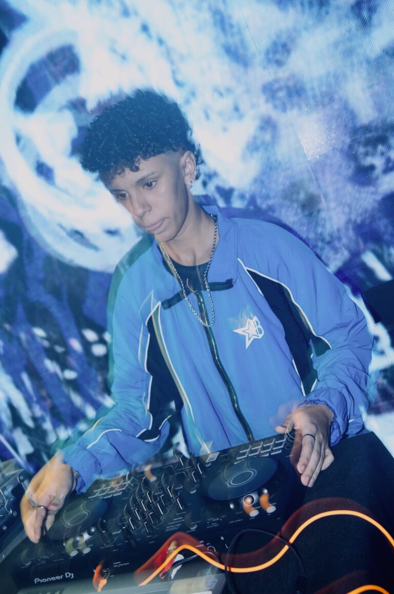 DJ de jaqueta azul com o telão claro atrás — Sad Baile Joker, Halloween em São Paulo, 17/10/2026