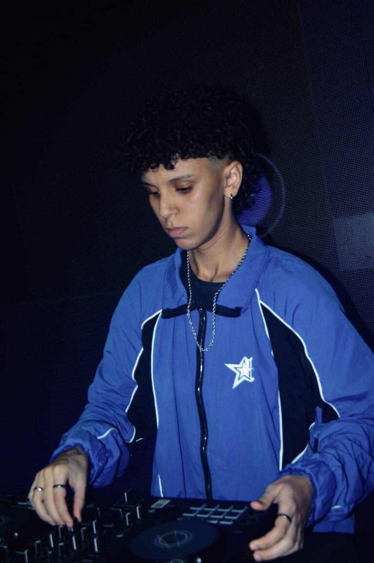 DJ de jaqueta azul concentrado nos controles — Sad Baile Joker, Halloween em São Paulo, 17/10/2026
