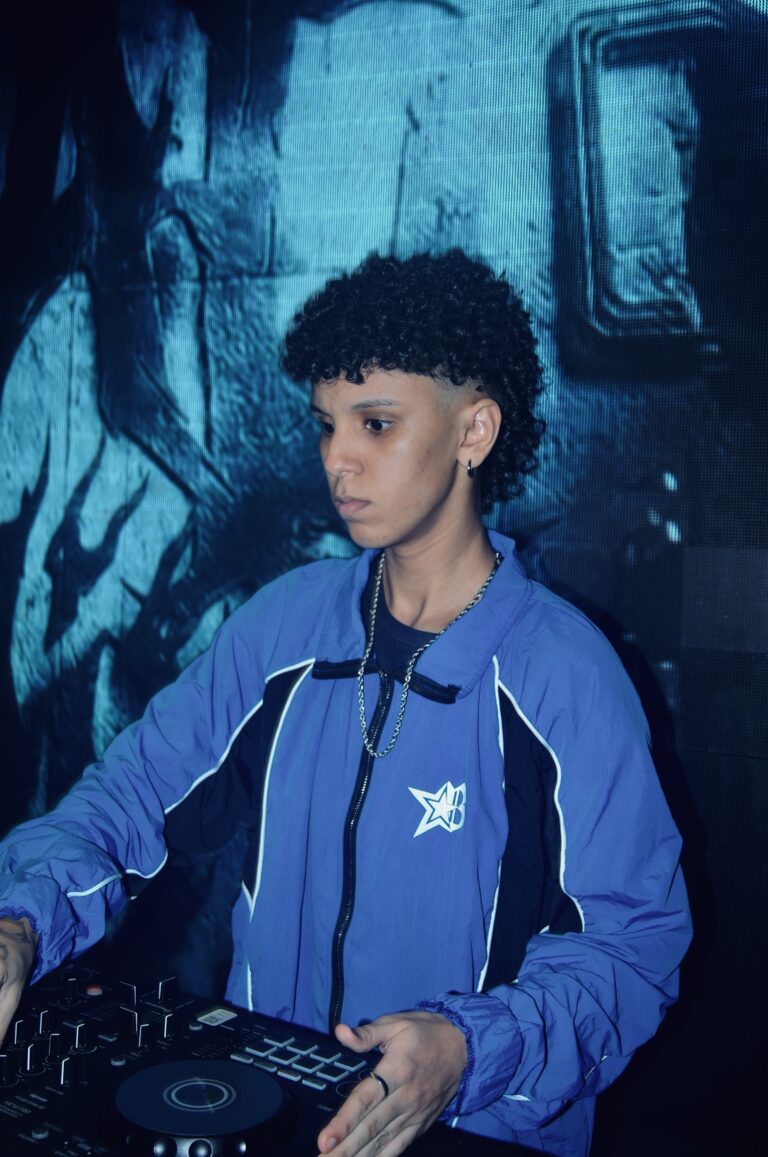 DJ de jaqueta azul diante do telão azul — Sad Baile Joker, Halloween em São Paulo, 17/10/2026