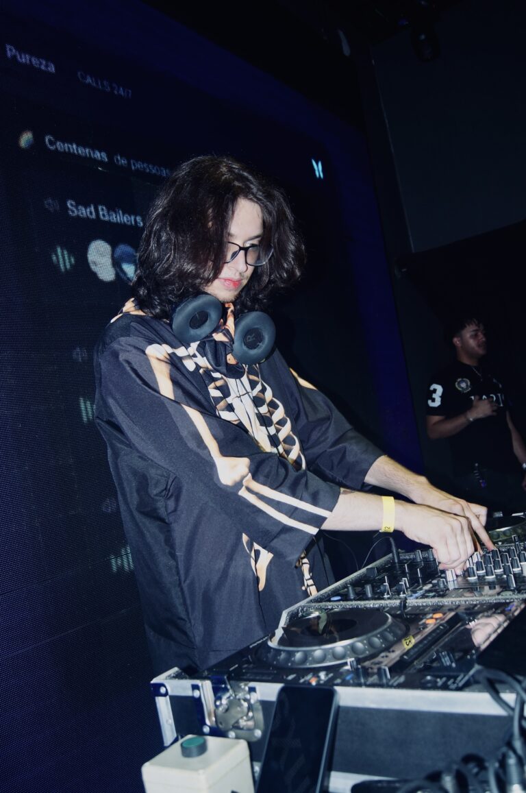 DJ de óculos mixando diante do telão de mensagens — Sad Baile Joker, Halloween em São Paulo, 17/10/2026