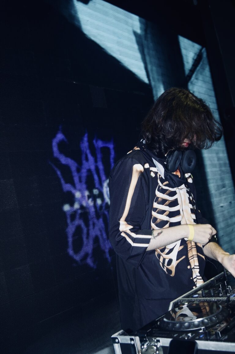 DJ de jaqueta de esqueleto com o logo roxo ao lado — Sad Baile Joker, Halloween em São Paulo, 17/10/2026