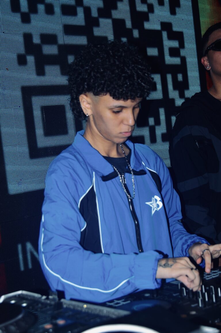 DJ de jaqueta azul diante do QR code, em outro ângulo — Sad Baile Joker, Halloween em São Paulo, 17/10/2026