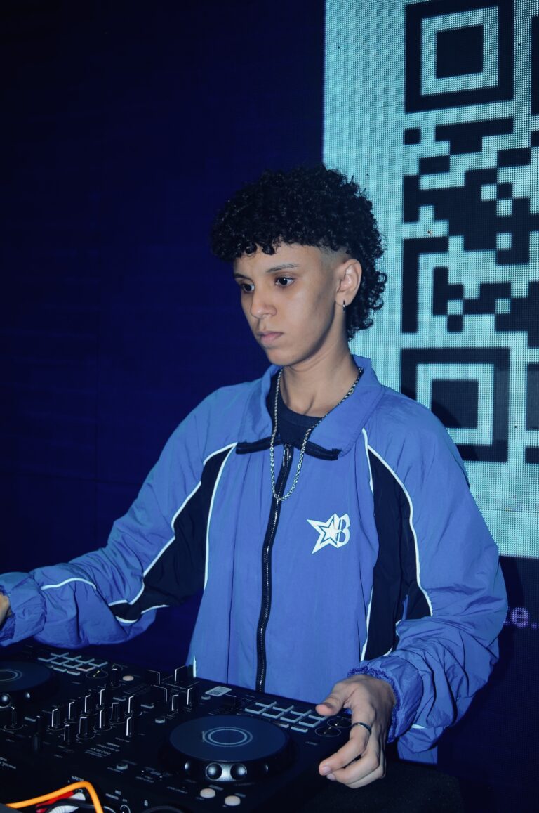 DJ de jaqueta azul ao lado do QR code iluminado — Sad Baile Joker, Halloween em São Paulo, 17/10/2026