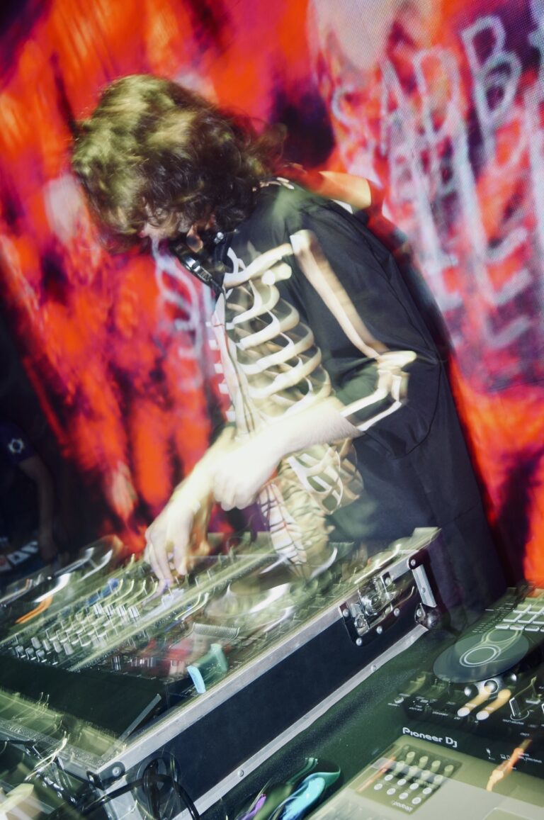 DJ de jaqueta de esqueleto diante do telão vermelho — Sad Baile Joker, Halloween em São Paulo, 17/10/2026