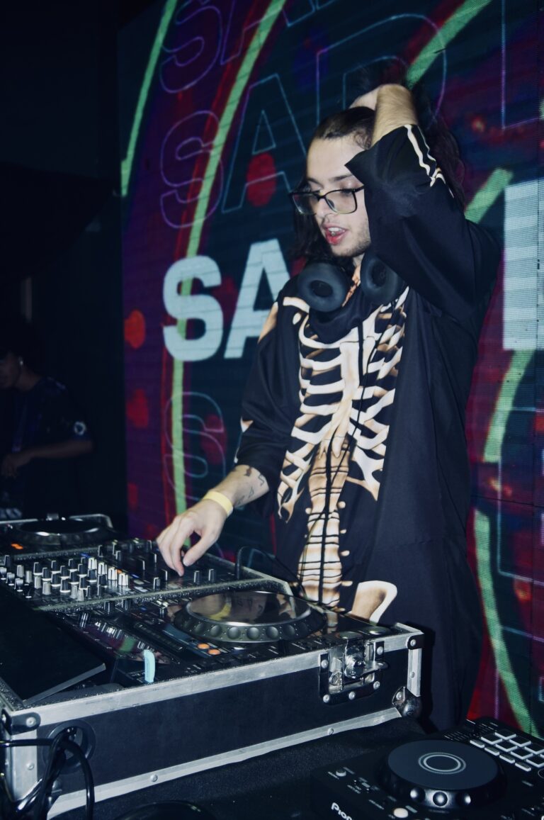 DJ de jaqueta de esqueleto com a mão na cabeça — Sad Baile Joker, Halloween em São Paulo, 17/10/2026