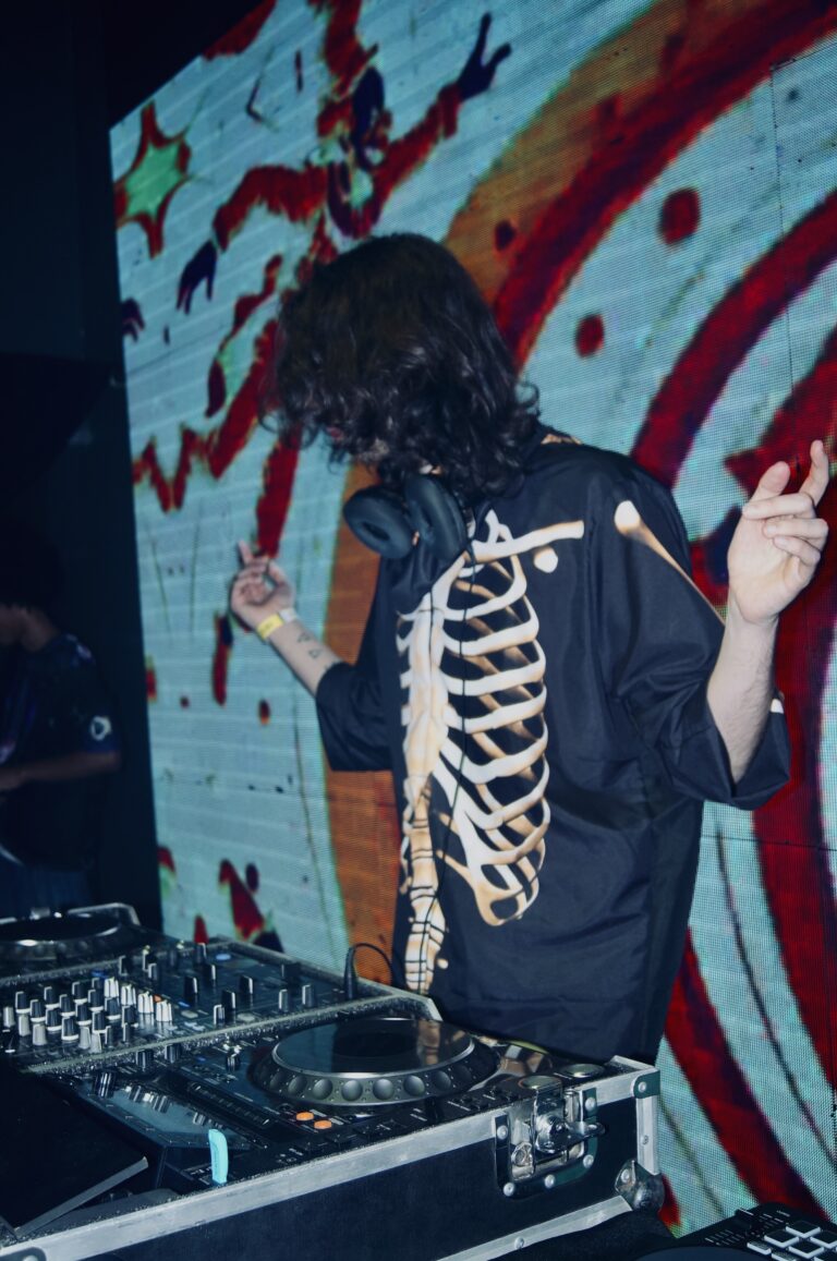 DJ de jaqueta de esqueleto dança diante do telão colorido — Sad Baile Joker, Halloween em São Paulo, 17/10/2026