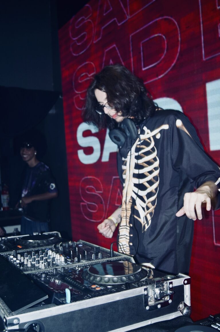 DJ de jaqueta de esqueleto com o letreiro Sad em vermelho — Sad Baile Joker, Halloween em São Paulo, 17/10/2026
