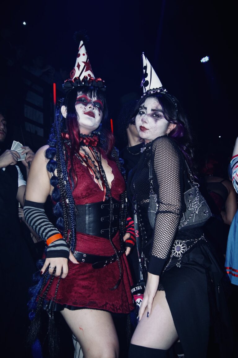 Amigas de chapéu de palhaço sob luz azul — Sad Baile Joker, Halloween em São Paulo, 17/10/2026