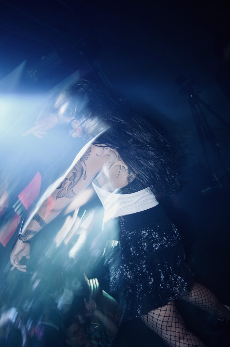 Garota de saia dança no palco sob luz azul — Sad Baile Joker, Halloween em São Paulo, 17/10/2026