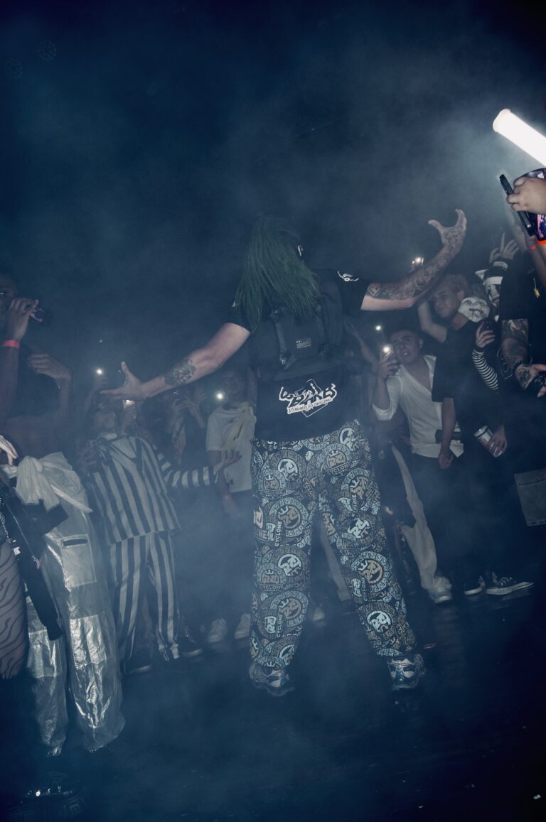 Artista de calça estampada em meio à fumaça — Sad Baile Joker, Halloween em São Paulo, 17/10/2026