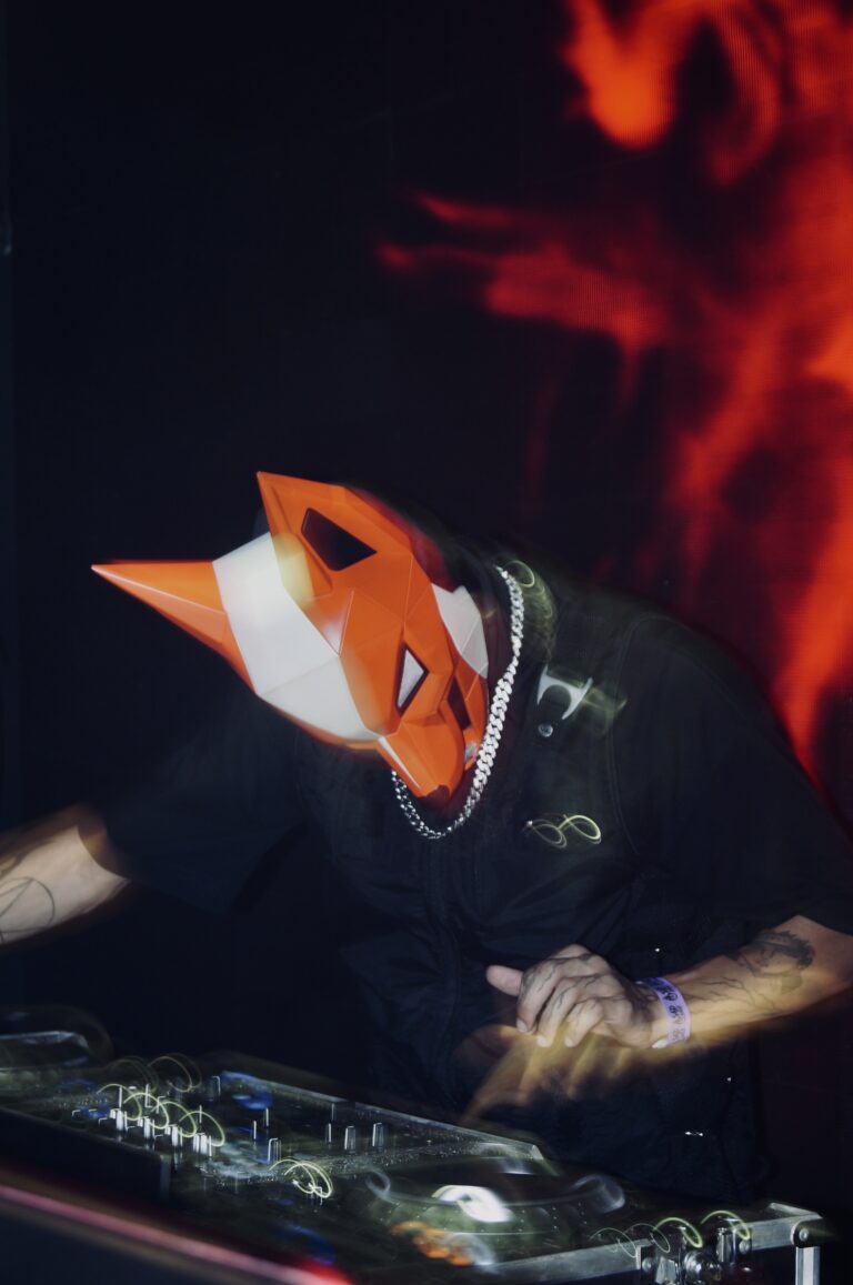 DJ mascarado de raposa diante do telão de fogo, em outro ângulo — Sad Baile Joker, Halloween em São Paulo, 17/10/2026