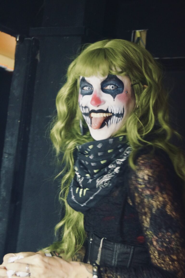 Maquiadora com peruca verde e maquiagem de palhaço — Sad Baile Joker, Halloween em São Paulo, 17/10/2026