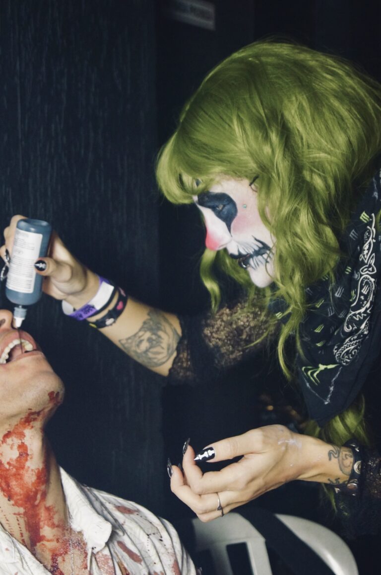Maquiadora derrama sangue falso no rosto de um participante — Sad Baile Joker, Halloween em São Paulo, 17/10/2026