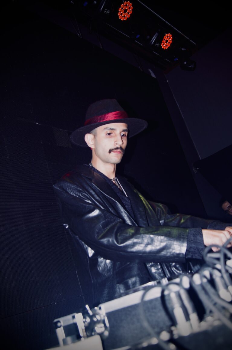 DJ de chapéu e jaqueta de couro na cabine escura — Sad Baile Joker, Halloween em São Paulo, 17/10/2026