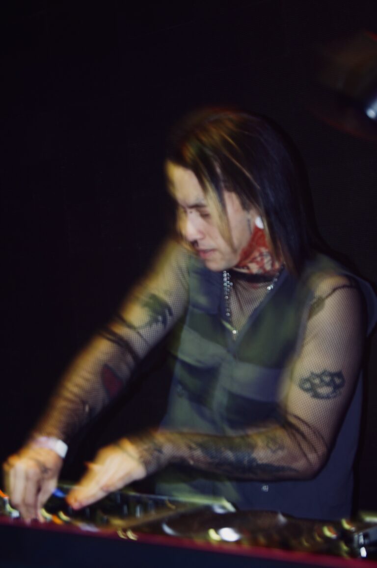 DJ de cabelo comprido e blusa de tela nos controles — Sad Baile Joker, Halloween em São Paulo, 17/10/2026