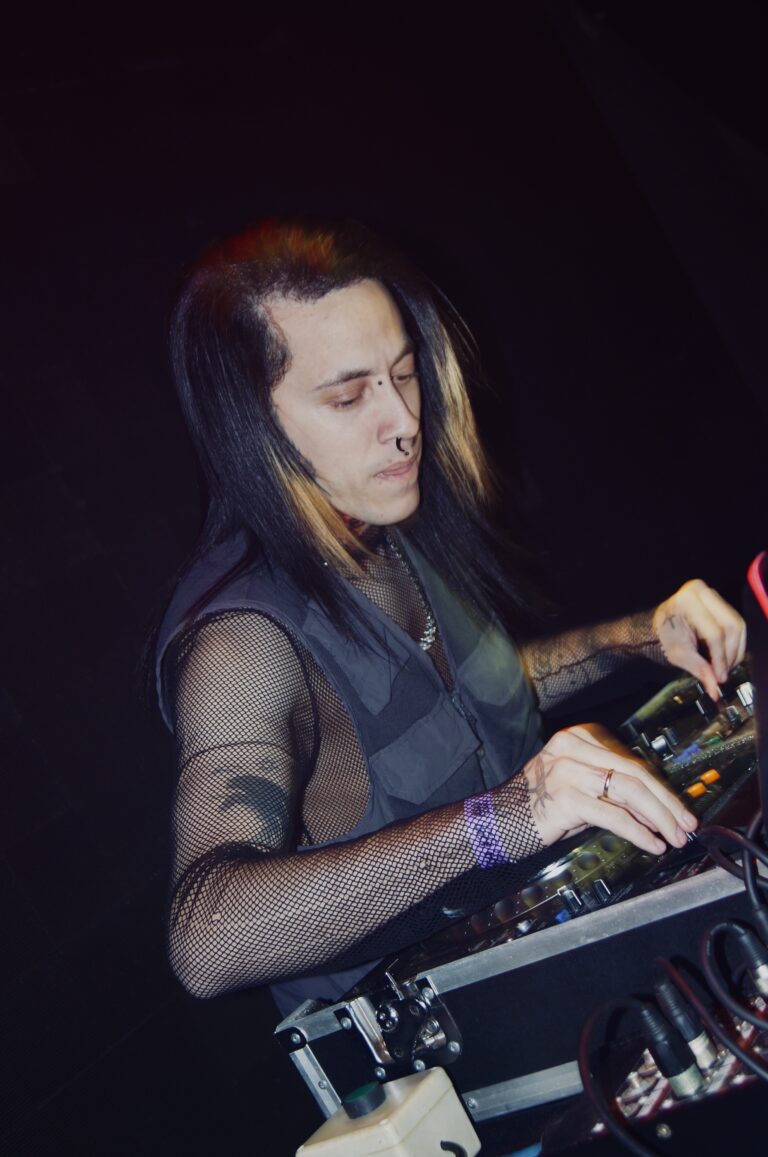 DJ de cabelo comprido olha para o mixer — Sad Baile Joker, Halloween em São Paulo, 17/10/2026