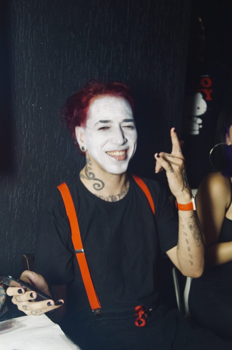 Rapaz de suspensórios e rosto pintado sorri — Sad Baile Joker, Halloween em São Paulo, 17/10/2026