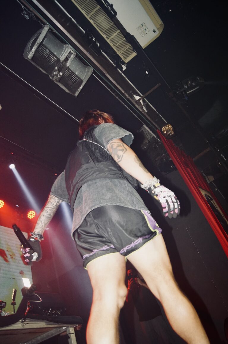Artista de shorts no palco sob luzes vermelhas — Sad Baile Joker, Halloween em São Paulo, 17/10/2026