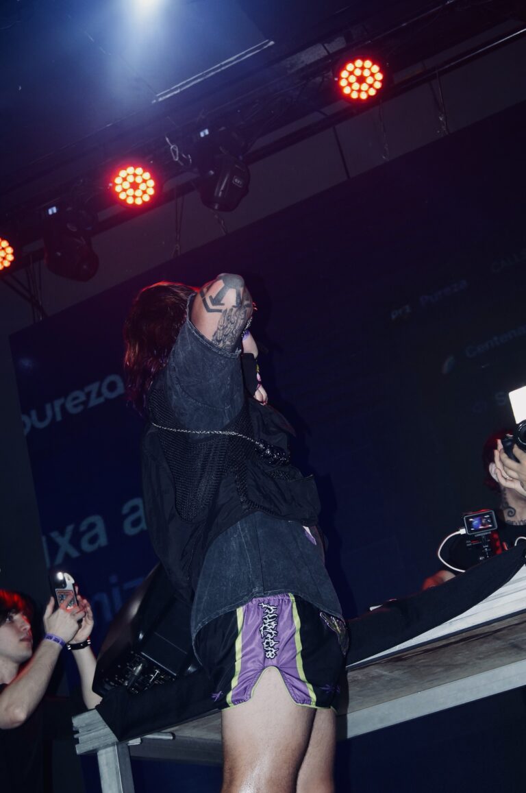 Artista canta na mesa do palco sob luzes vermelhas — Sad Baile Joker, Halloween em São Paulo, 17/10/2026