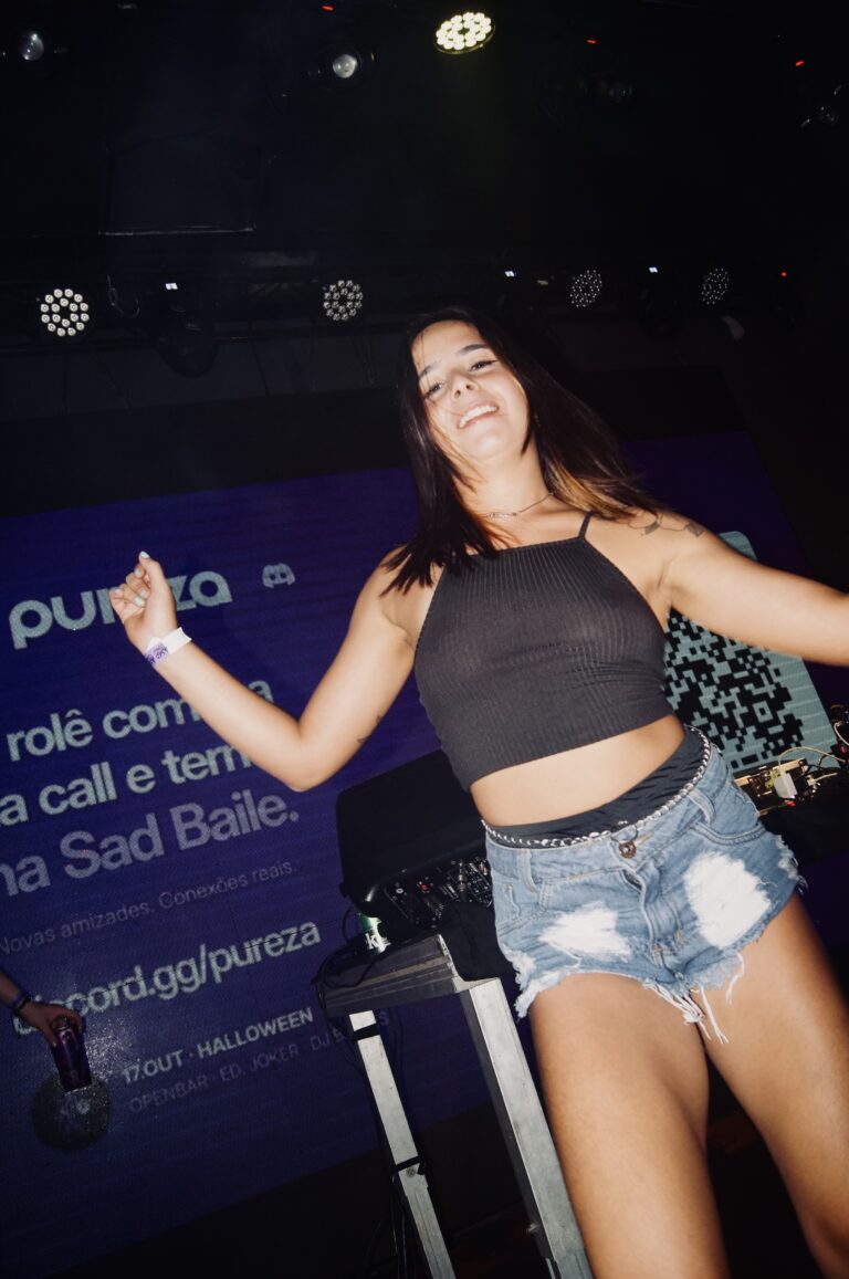 Garota de top e shorts jeans dança diante do telão — Sad Baile Joker, Halloween em São Paulo, 17/10/2026