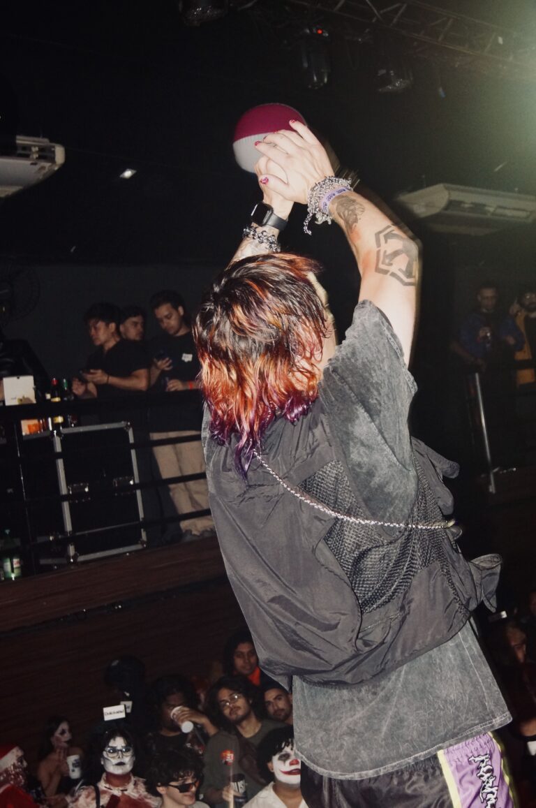 Artista ergue o microfone de costas para a câmera — Sad Baile Joker, Halloween em São Paulo, 17/10/2026